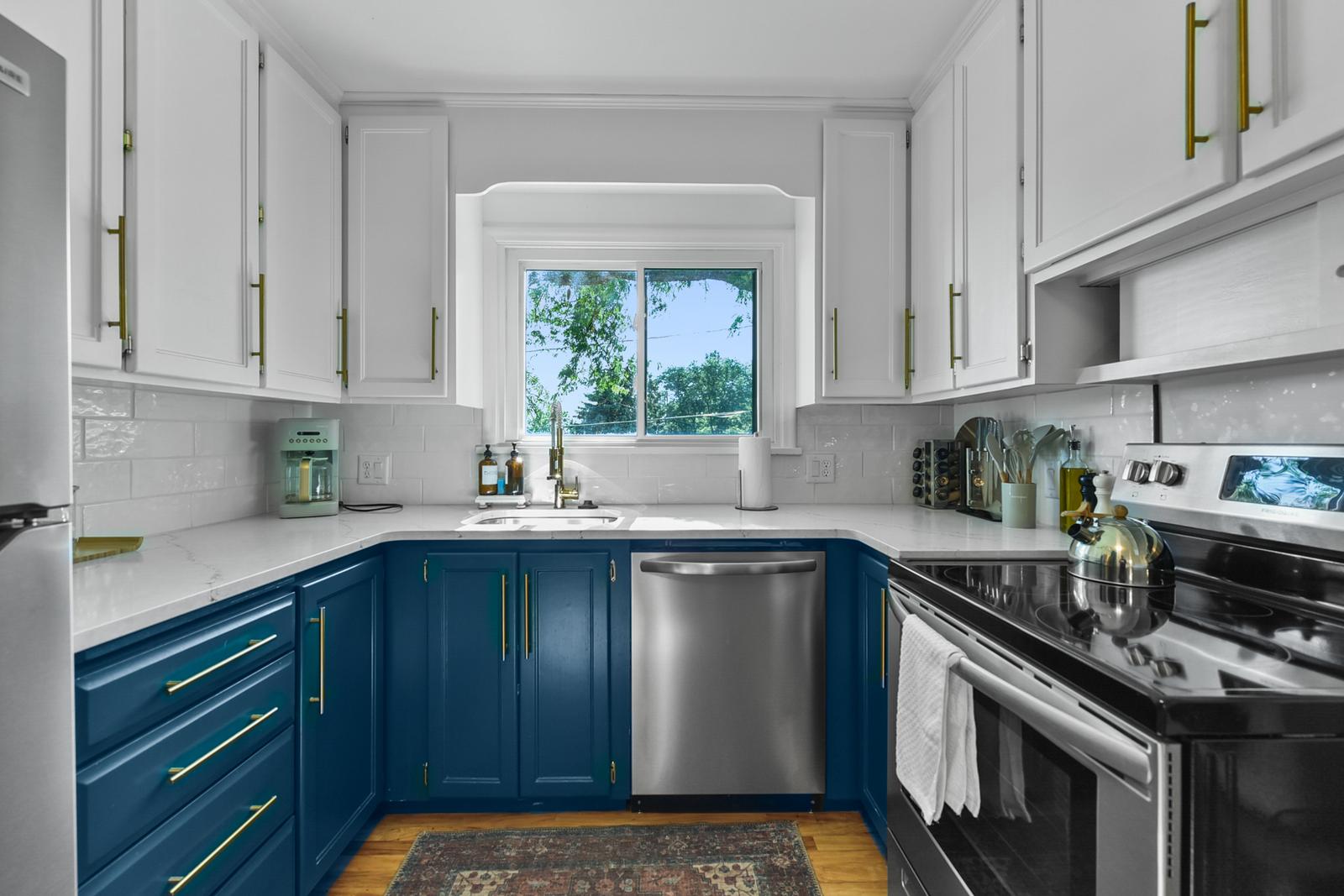 Cook your favorite meals in this bright, modern kitchen featuring elegant two-tone cabinetry and sleek stainless steel appliances.