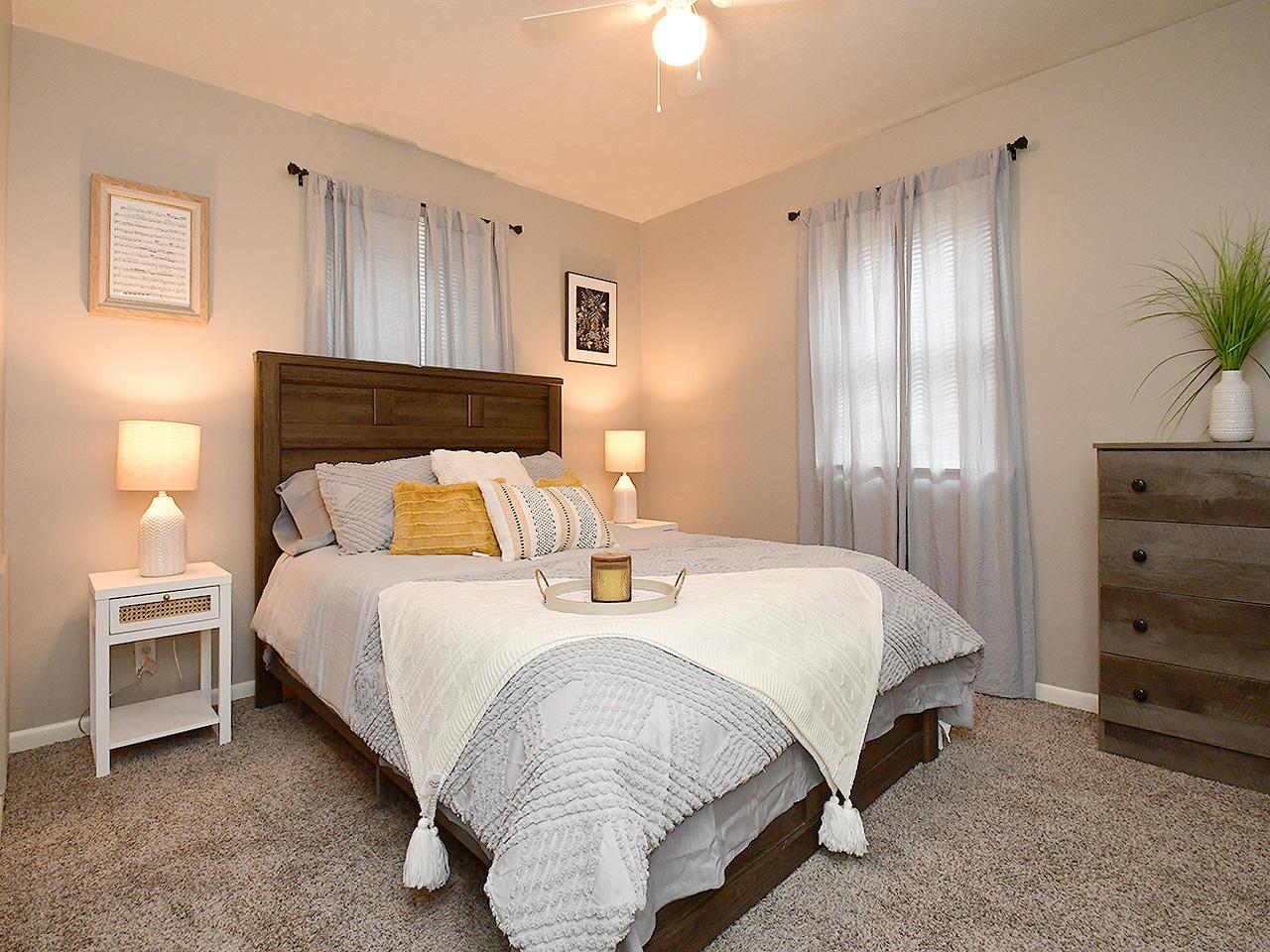 Sink into crisp white linens and let natural light filter through sheer curtains as you unwind in your peaceful bedroom retreat with warm ambient lighting.