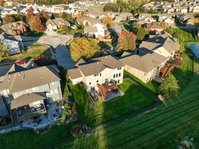 Aerial view showcases the property nestled within a peaceful suburban neighborhood, surrounded by autumn foliage and well-maintained homes.