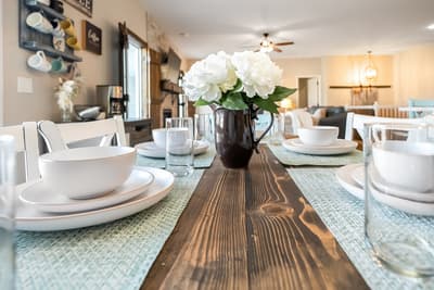 Gather around this beautifully set dining table where fresh flowers and elegant place settings await your memorable meals together.