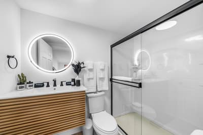 Unwind in your sleek bathroom featuring a luxurious walk-in shower, illuminated mirror, and modern wood vanity for your daily rituals.