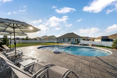 Dive into your private oasis with this stunning pool featuring volleyball net, surrounded by comfortable loungers and umbrellas for perfect sunny relaxation.