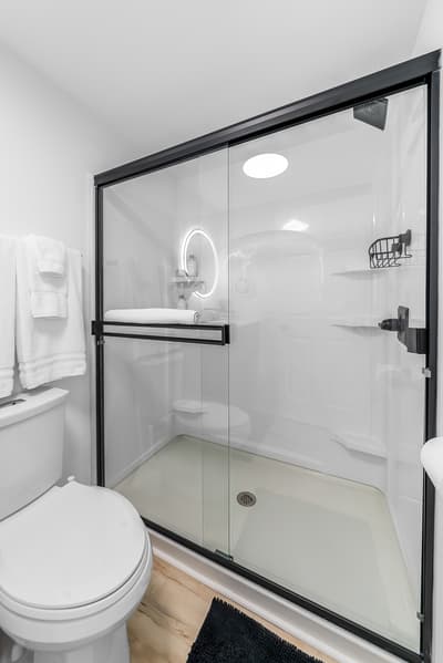 Step into your sleek, modern bathroom featuring a spacious glass-enclosed shower with premium fixtures and fresh white towels waiting for you.