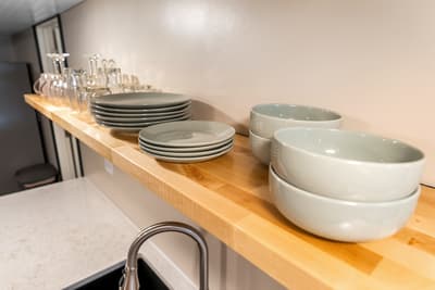 Your beautifully organized kitchen shelf displays everything you need for memorable meals, with stylish plates, bowls, and glassware ready for your culinary adventures.