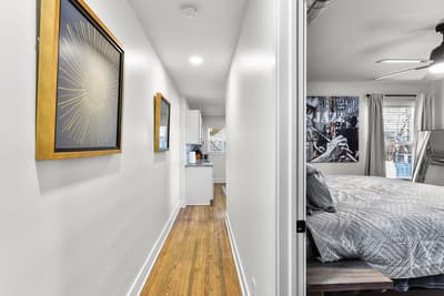 Step into your stylish hallway where warm hardwood floors and curated artwork create an inviting path to your comfortable bedroom retreat.