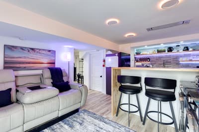 Unwind in your sleek basement retreat with plush recliners, modern bar seating, and ambient lighting creating the perfect entertainment space.