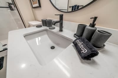 Your elegant bathroom features a pristine white vanity with sleek black fixtures and thoughtful amenities to make your stay comfortable.