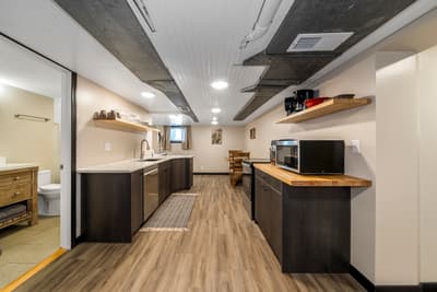 Your stylish basement kitchen features modern dark cabinets, butcher-block counters, and all essentials for comfortable meal prep.