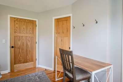 Your dedicated workspace awaits with a sturdy wooden desk and chair, plus convenient wall hooks for your belongings.