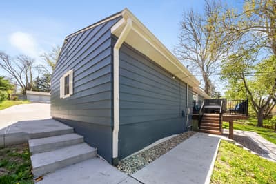 Modern vacation rental featuring sleek blue siding and contemporary design, nestled in a peaceful residential neighborhood with mature trees.