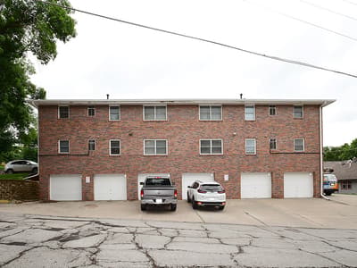 This multi-unit brick property features individual garages and parking spaces, set in a tree-lined residential neighborhood with convenient access to local amenities.