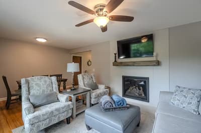 Unwind in your cozy living space featuring plush seating, warm fireplace, and ceiling fan for perfect comfort year-round.