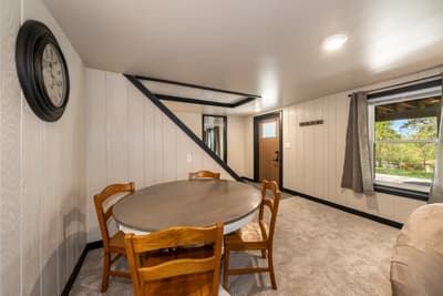 Your cozy dining nook features a round table perfect for intimate meals, with charming nautical touches and peaceful garden views through the window.