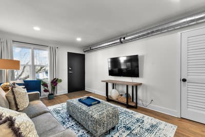 Relax in your stylish living room with modern furnishings, wall-mounted TV, and industrial-chic exposed ductwork creating urban sophistication.