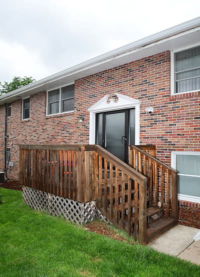 Classic brick exterior with a welcoming entrance ramp, set in a peaceful residential neighborhood surrounded by lush greenery and mature trees.
