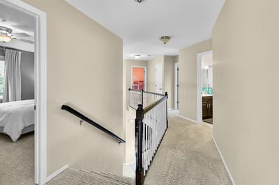 Navigate the inviting upstairs hallway where plush carpeting cushions your steps to multiple well-appointed bedrooms and private bathrooms.
