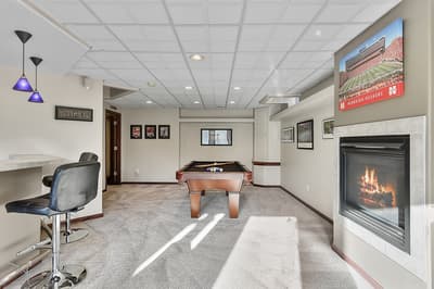 Unwind in your private game room featuring a pool table, cozy fireplace, and bar seating for memorable evenings.