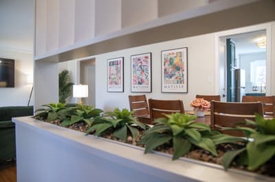 Unwind at your elegant dining table surrounded by vibrant Matisse prints and lush greenery that brings warmth to every meal.