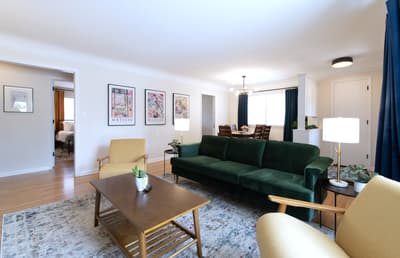 Sink into the plush emerald sofa and unwind in your stylish living space, complete with curated art and warm lighting for cozy evenings.