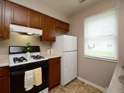 Your fully equipped kitchen features warm wood cabinetry, a gas stove, full-size refrigerator, and plenty of natural light streaming through the window—perfect for preparing home-cooked meals during your stay.