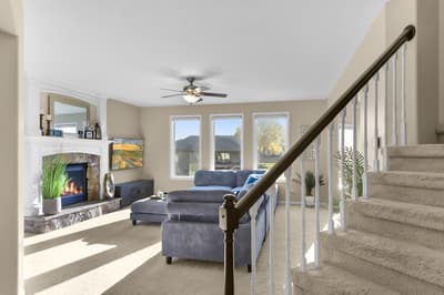 Relax in your spacious living room with crackling fireplace, plush sectional, and sunlight streaming through large windows.