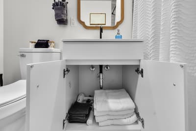 Your modern bathroom features smart storage solutions with fluffy towels and toiletries neatly organized beneath the sleek vanity.