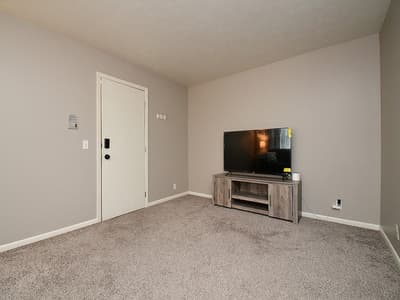 A clean, spacious living area awaits your arrival, offering soft carpet underfoot and a minimalist design that makes the space feel open and calming.