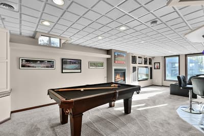Challenge friends to a game in this spacious recreation room featuring pool table, cozy fireplace, and comfortable seating.