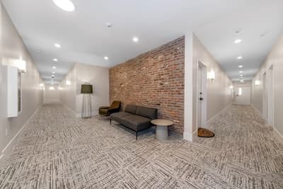 Relax in this stylish communal lounge featuring exposed brick walls, comfortable seating, and modern lighting for your downtime.