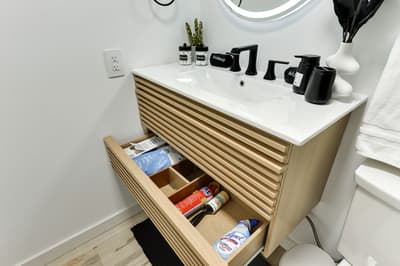 Your modern bathroom features a stylish floating vanity with organized storage drawers filled with thoughtful amenities for your comfort.