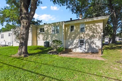 Charming two-story home nestled under mature shade trees in a peaceful residential neighborhood with spacious green lawn.