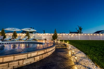 Beautiful evening pool area with elegant stone features, atmospheric lighting, and manicured landscaping creating a serene outdoor retreat.