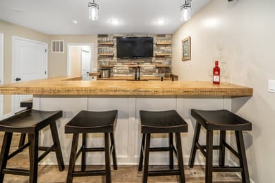 Your stylish bar area features warm wood countertops and modern stools, perfect for casual dining or evening drinks while enjoying entertainment.