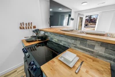 Cook your favorite meals in this stylish kitchen featuring warm wood countertops, sleek stone backsplash, and modern appliances.