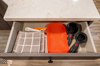 Your kitchen drawer is thoughtfully stocked with essentials - colorful cookware and measuring tools ready for your culinary adventures.