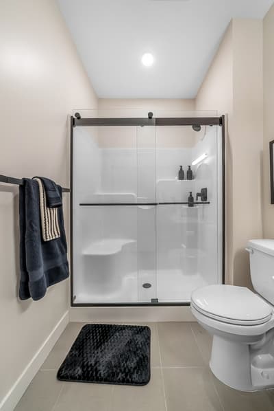 Step into your sleek private bathroom featuring a modern glass-enclosed shower and fresh towels waiting for your arrival.