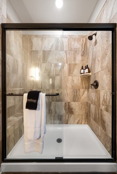Step into your luxurious marble shower with sleek glass doors, perfect for refreshing after your adventures.