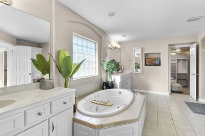 Unwind in your luxurious spa-like bathroom with a soaking tub and tropical plants creating a serene retreat.