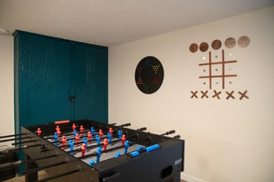 Challenge friends to foosball in your own game room, complete with dartboard and playful wall art for endless entertainment.