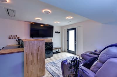 Unwind in your stylish basement lounge with plush seating, modern kitchen island, and entertainment setup for cozy evenings.