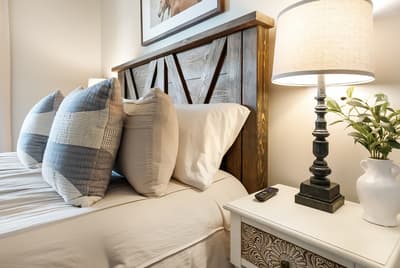 Unwind in your cozy bedroom featuring a handcrafted wooden headboard, soft linens, and thoughtful touches like bedside lighting.