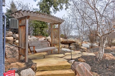 Relax on your private wooden swing surrounded by natural stone landscaping and mature trees in this peaceful outdoor retreat.