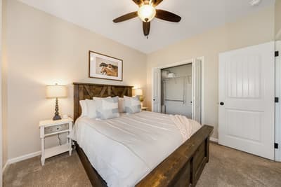 Sink into crisp white linens on your rustic wooden bed, perfectly cooled by the ceiling fan overhead in this cozy bedroom retreat.