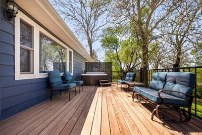 Sink into plush blue cushions on your private deck, where morning coffee tastes better and evening conversations flow naturally under towering trees.