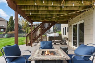 Your private outdoor oasis awaits with cozy fire pit seating, perfect for evening gatherings under twinkling string lights and covered pergola comfort.