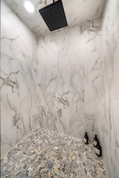 Step into your luxurious marble-wrapped shower sanctuary, where rainfall cascades from overhead while premium amenities await your indulgent retreat.