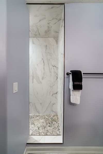 Step into your luxurious marble-tiled shower with elegant pebble flooring and spa-like ambiance for the ultimate relaxation.