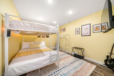 Relax in your cozy bunk bedroom with cheerful yellow walls, artistic touches, and thoughtful amenities for a comfortable stay.