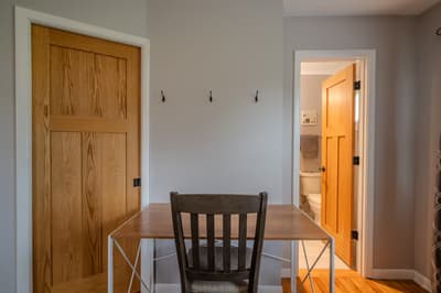 Your cozy dining nook features a warm wood table perfect for morning coffee or planning adventures, with convenient wall hooks for your gear.