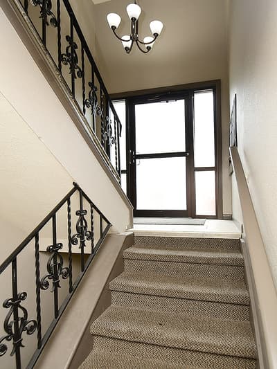 The ornate wrought-iron staircase and elegant chandelier welcome you to this beautifully appointed property, where thoughtful details create an inviting first impression.